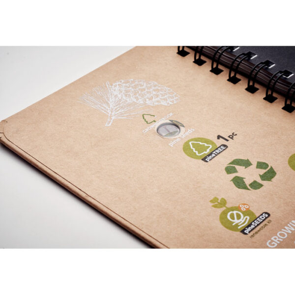 Libreta ecológica GROWNOTEBOOK™ con semillas de pino en la tapa y espiral metálico, ideal para promociones sostenibles con impacto positivo.