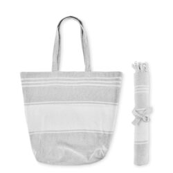 Set de playa azul HUMMUM compuesto por toalla fouta enrollada y bolsa tote de rayas con flecos.